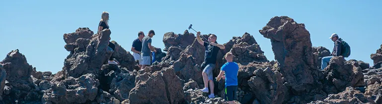 Eine Person klettert an einer Felswand, fokussiert und sichernd in der Höhe.