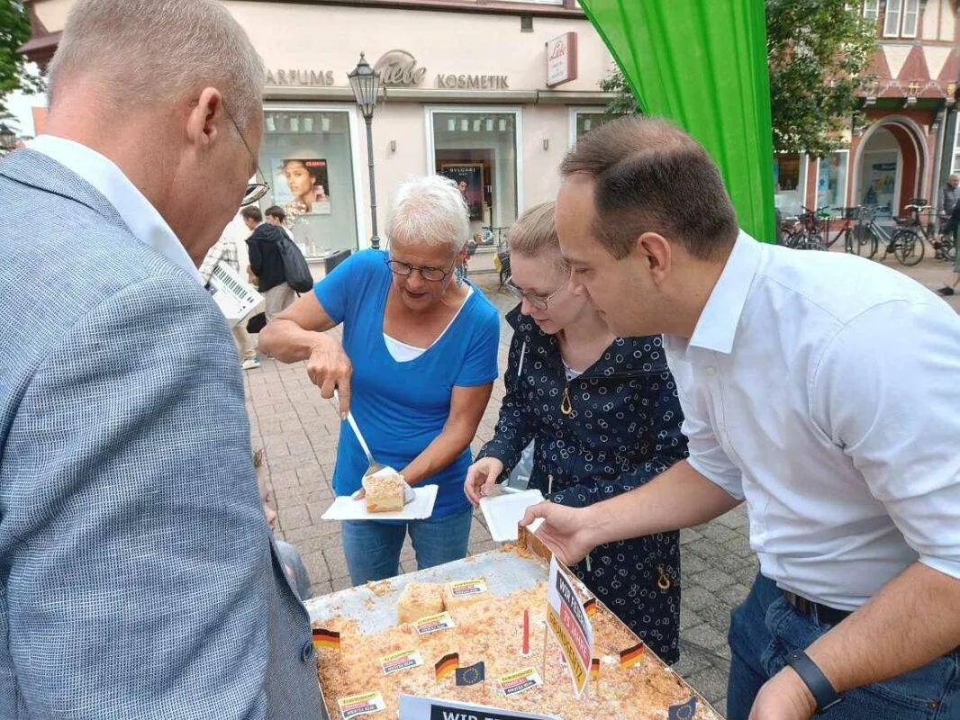 Eine Person mit einem Tablett voll Kuchen nähert sich einem anderen Stand im Freien