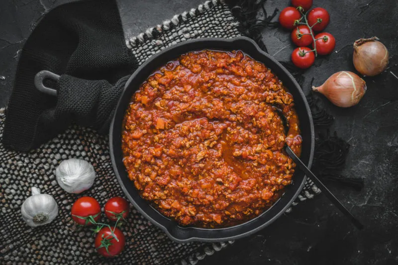 Eine Pfanne gefüllt mit fertig gekochter Bolognesesoße aus dem pflanzlichen Hackfleischersatz, vermischt mit Gemüse und Tomaten.