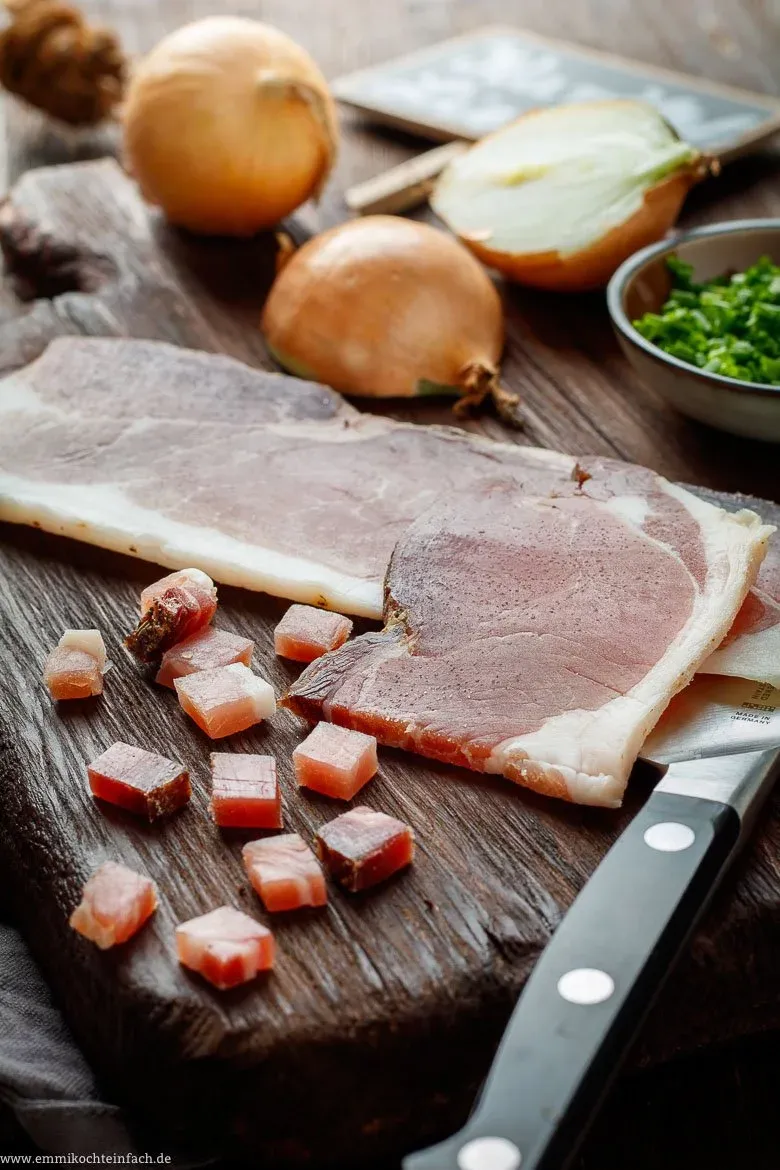 Eine Pfanne mit ausgelassenem Speck und glasigen Zwiebeln, bereit zum Unterheben unter die Bratkartoffeln