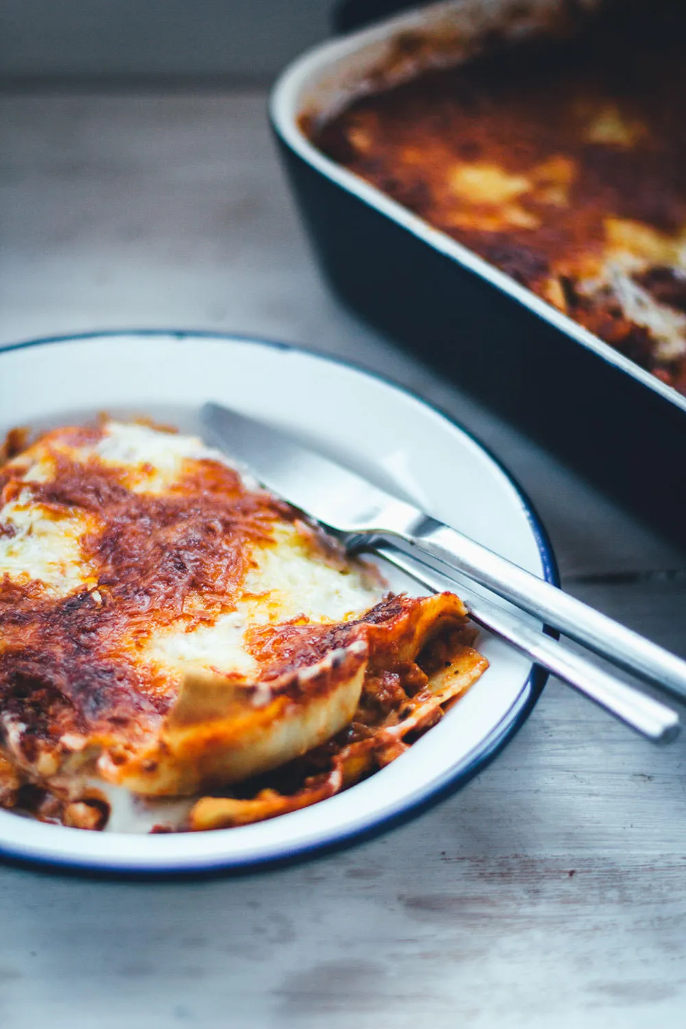Eine Portion Lasagne al forno, dampfend heiß aus dem Ofen, mit geschmolzenem Käse und Tomatensoße.