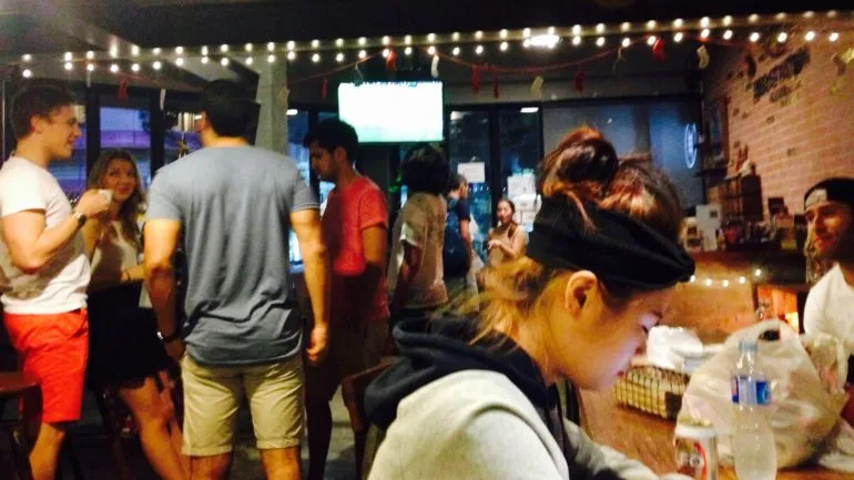 Eine Reisende sitzt in einem Hostel und unterhält sich mit anderen Backpackern