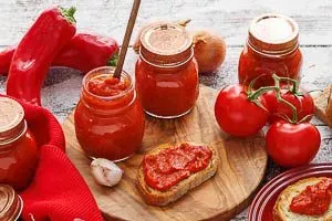 Eine Schale mit frischem, cremigem Ajvar, garniert mit einem Basilikumblatt, als Ergebnis des einfachen Rezepts