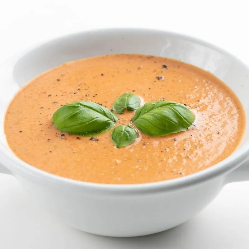 Eine Schüssel cremiger, schnell zubereiteter Low Carb Tomatensuppe, garniert mit frischen Kräutern