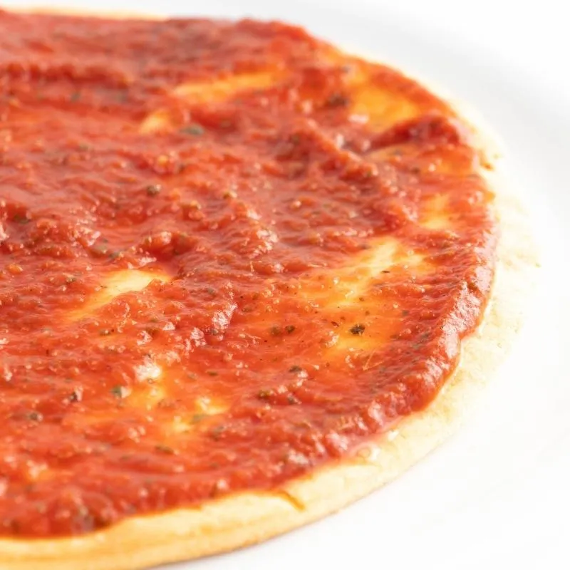 Eine Schüssel mit hausgemachter Keto Pizza Sauce, die eine reichhaltige rote Farbe hat und mit frischen Kräutern garniert ist. Alt-Text: Keto Pizza Sauce Rezept - Die perfekte Grundlage für Ihre ketogene Pizza