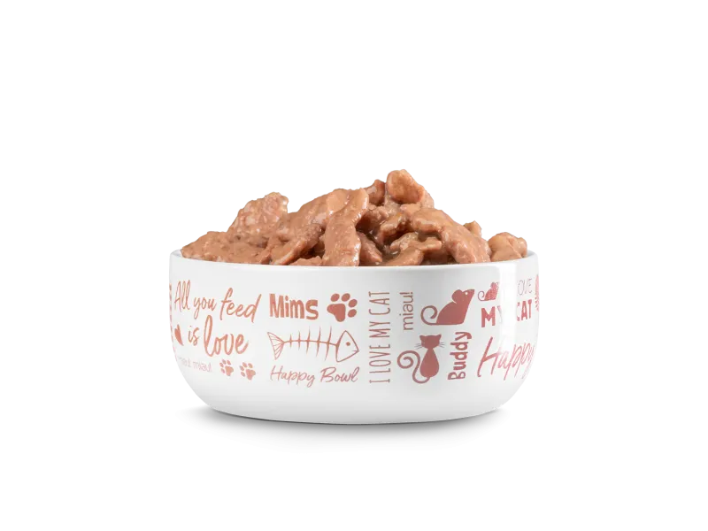 Eine Schüssel mit herzhaftem, braunem Katzenfutter, umgeben von Happy Cat Verpackungen.
