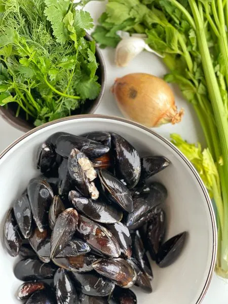 Eine Schüssel voller frisch zubereiteter Miesmuscheln in einer cremig-würzigen Soße, verziert mit frischen Kräutern.
