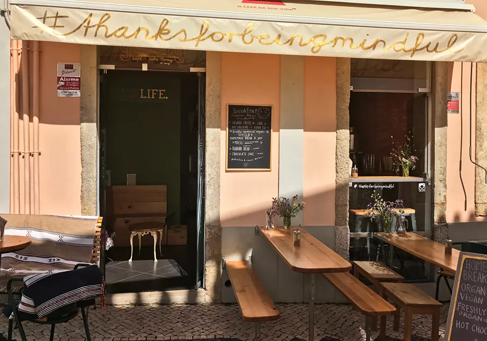 Eine Tasse Chai Latte mit Milchschaum und ein Teller mit getoastetem Brot, Pesto und getrockneten Tomaten