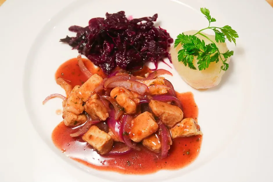 Eine vegetarische oder vegane Gans, kreativ zubereitet und serviert mit Knödeln und Blaukraut.
