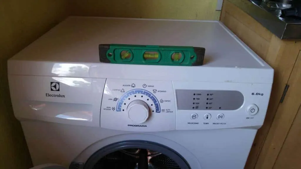 Eine Wasserwaage wird zum Ausnivellieren der Waschmaschine verwendet