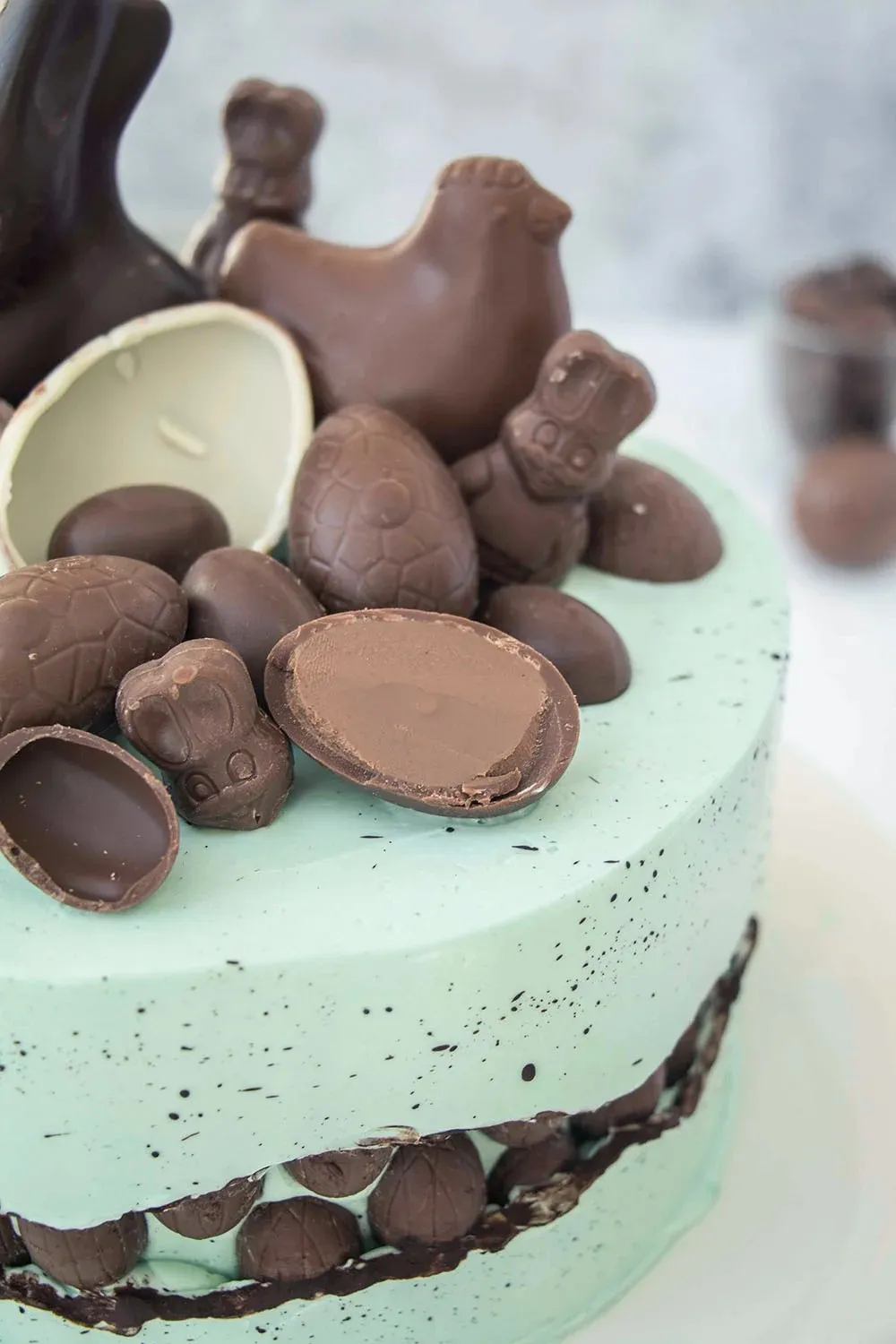 Eine wunderschön dekorierte Fault Line Ostertorte mit gesprenkelter blauer Buttercreme und halbierten Schokoladeneiern in der Bruchlinie.