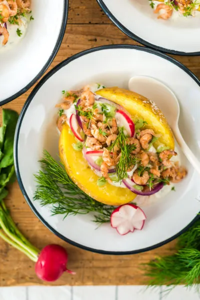 Eingelegte Radieschenscheiben und Zwiebelringe, vorbereitete Zutaten für die Ofenkartoffel mit Krabben.