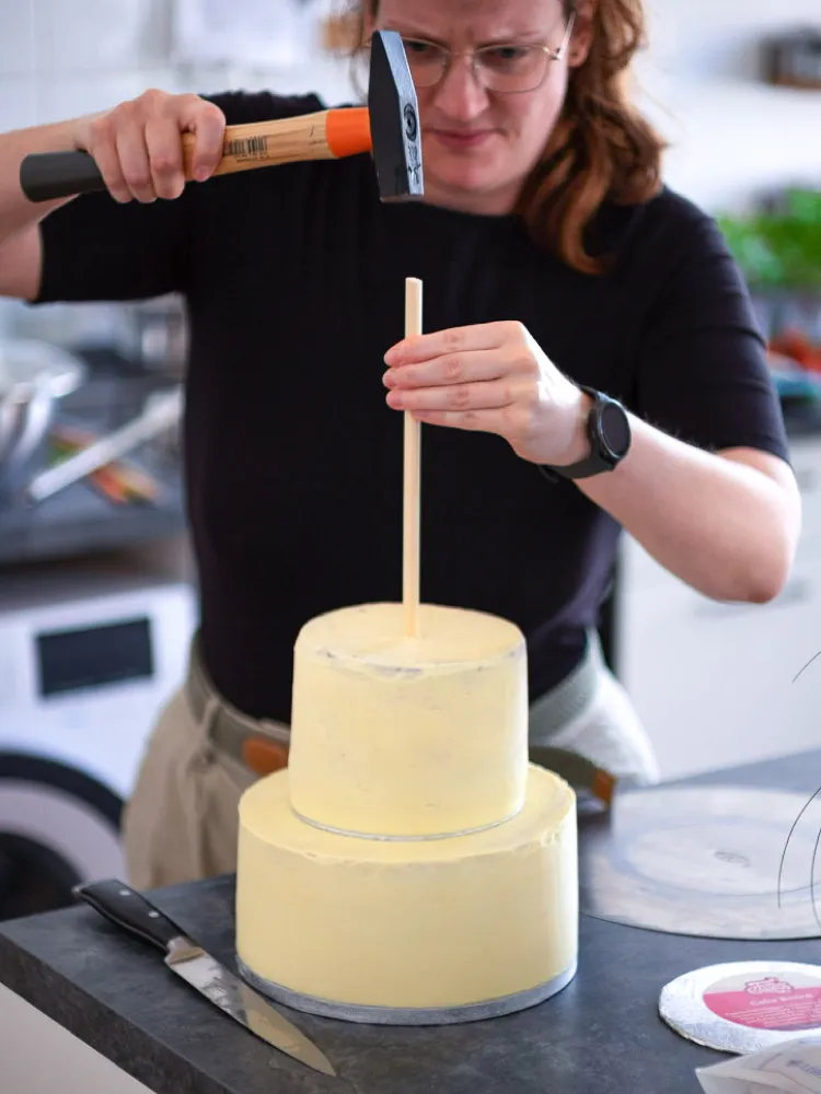 Einschlagen des mittigen Tortendübels in die gestapelte Hochzeitstorte