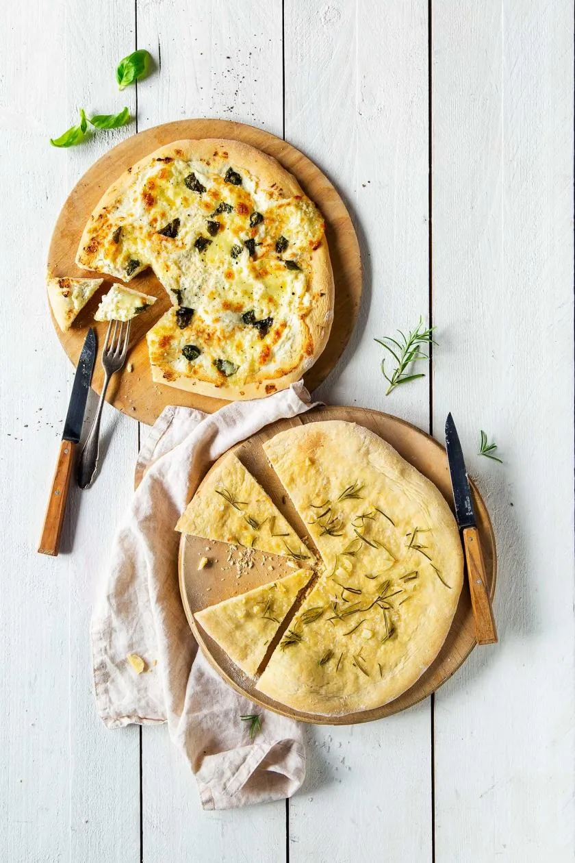 Elegante Pizza Bianca ohne Tomatensauce, belegt mit Ricotta und weiteren cremigen Zutaten.