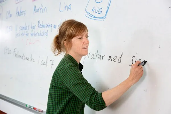 Engagierte Lehrerin in einer schwedischen Schulklasse, illustrierend die persönliche Betreuung im Notensystem des schwedischen Schulsystems.