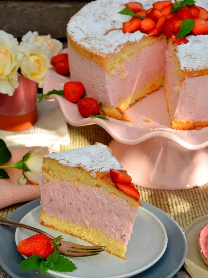 Erdbeer-Käsesahne-Torte, 1 Stück auf Teller, hinten die Torte