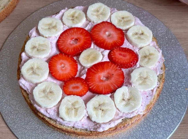 Erdbeer- und Bananenscheiben auf dem Kuchenboden als fruchtige Einlage für die Baby-Geburtstagstorte
