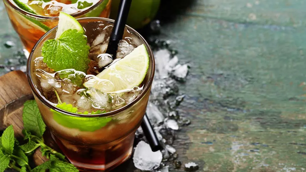 Erfrischender Nojito mit frischer Minze, Limettenspalten und Crushed Ice in einem hohen Glas, eine perfekte alkoholfreie Mojito-Alternative