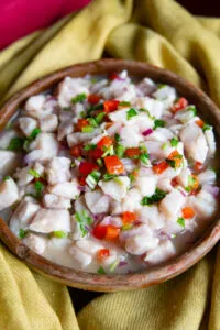 Exotisches Ceviche de Pescado in einer braunen Servierschale auf hellem Untergrund