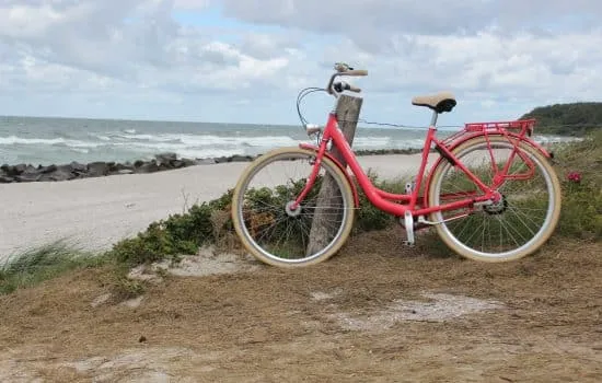 Fahrrad steht am Ostseestrand mit Dünen und Meer im Hintergrund