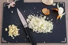 Fein gewürfelte Zwiebel und Knoblauch für die Hackfleischfüllung der Paprika