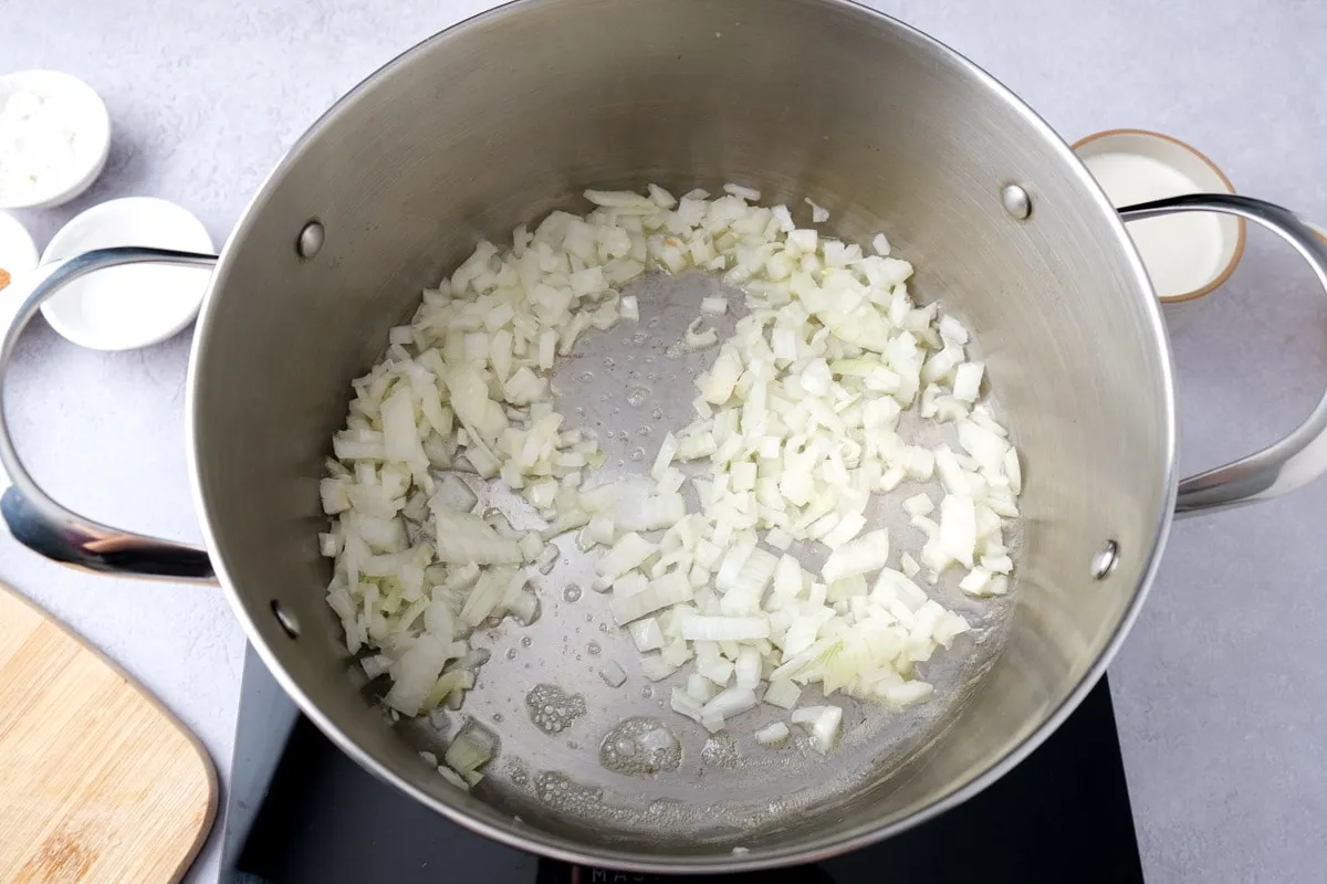 Fein gewürfelte Zwiebeln brutzeln in Butter in einem großen Topf für die Rahmwirsing-Basis.