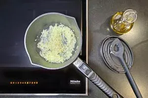 Fein gewürfelte Zwiebeln und Knoblauch werden in Olivenöl goldbraun angebraten als Basis für die Soße