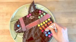 Feine Linien mit Zuckerschrift auf dem Pferdekopf-Kuchen für Details der Mähne und des Geschirrs