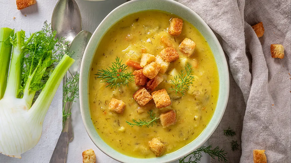 Fenchelsuppe mit Karotte und Kartoffel in einer Schüssel, garniert mit Croutons und frischen Kräutern.
