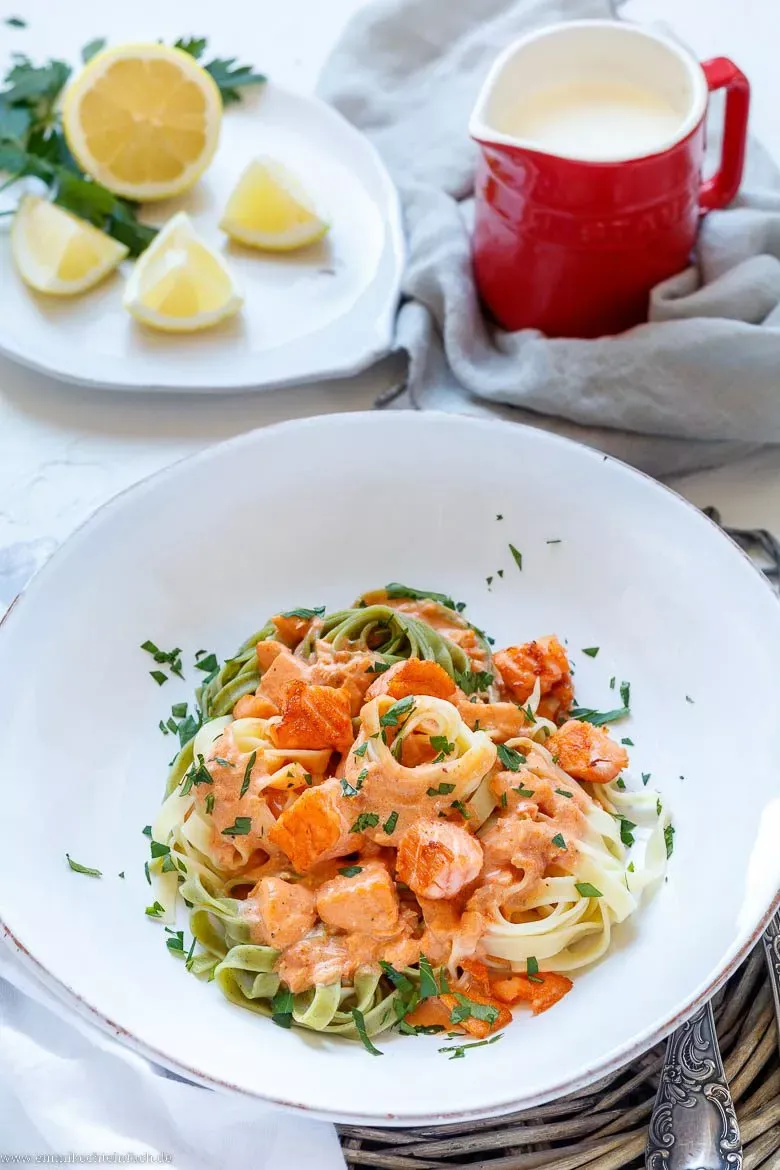 Fertig angerichtete Tagliatelle mit Lachs-Sahne-Soße auf einem Teller, garniert mit frischer Petersilie
