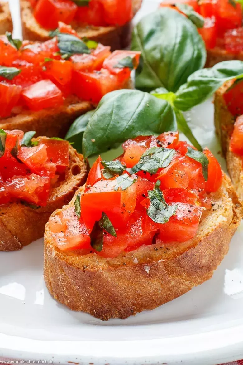 Fertig belegte Bruschetta mit Tomaten, Basilikum und Olivenöl auf einem Holzbrett