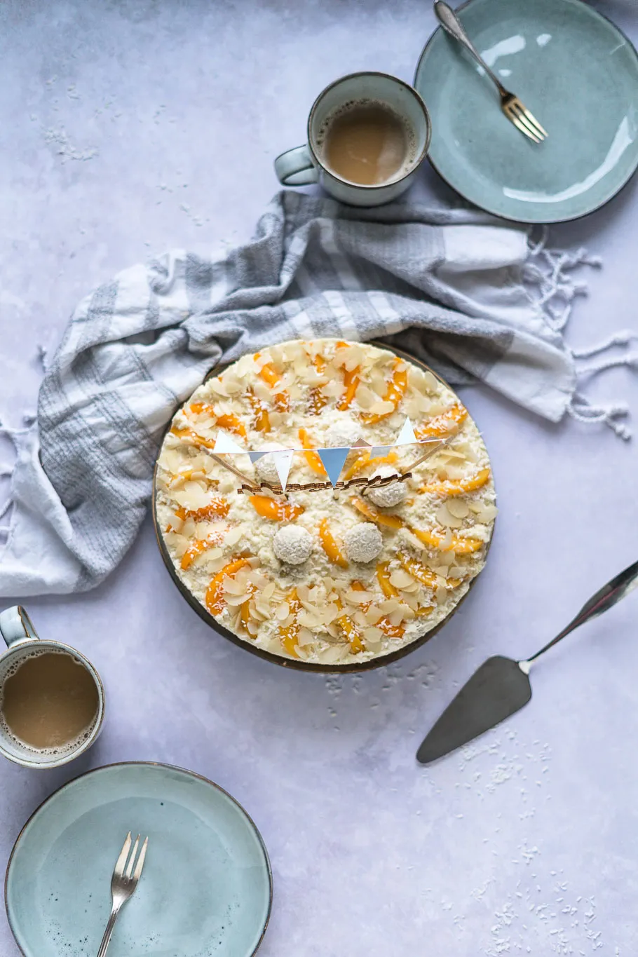 Fertig dekorierte Pfirsich-Maracuja-Raffaelo-Torte von oben, mit Kokosraspeln und Pfirsichscheiben