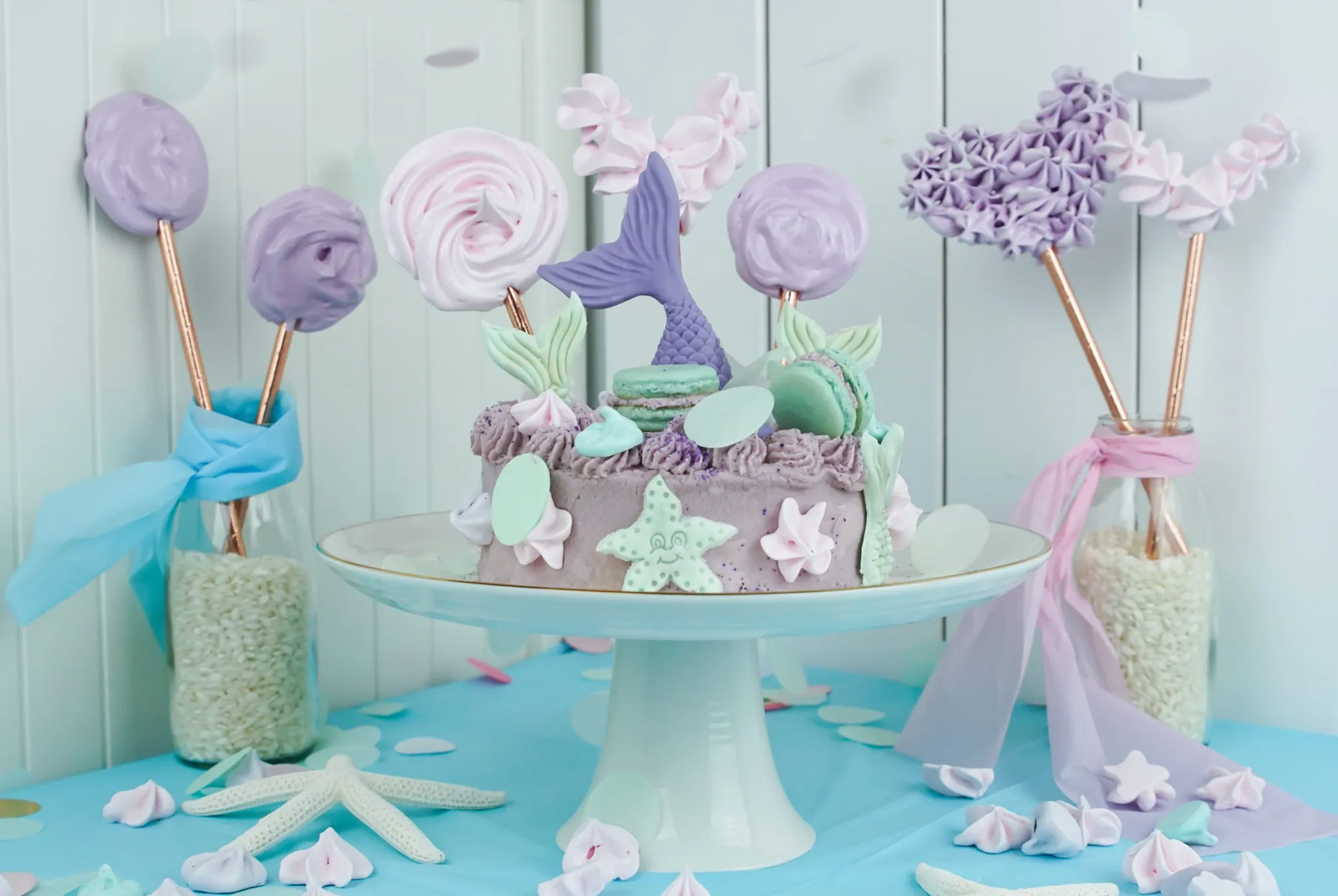 Fertig dekorierter Meerjungfrauen-Geburtstagskuchen mit mehrfarbiger Buttercreme, Baiser-Lollis und Meerjungfrauen-Flossen-Toppern