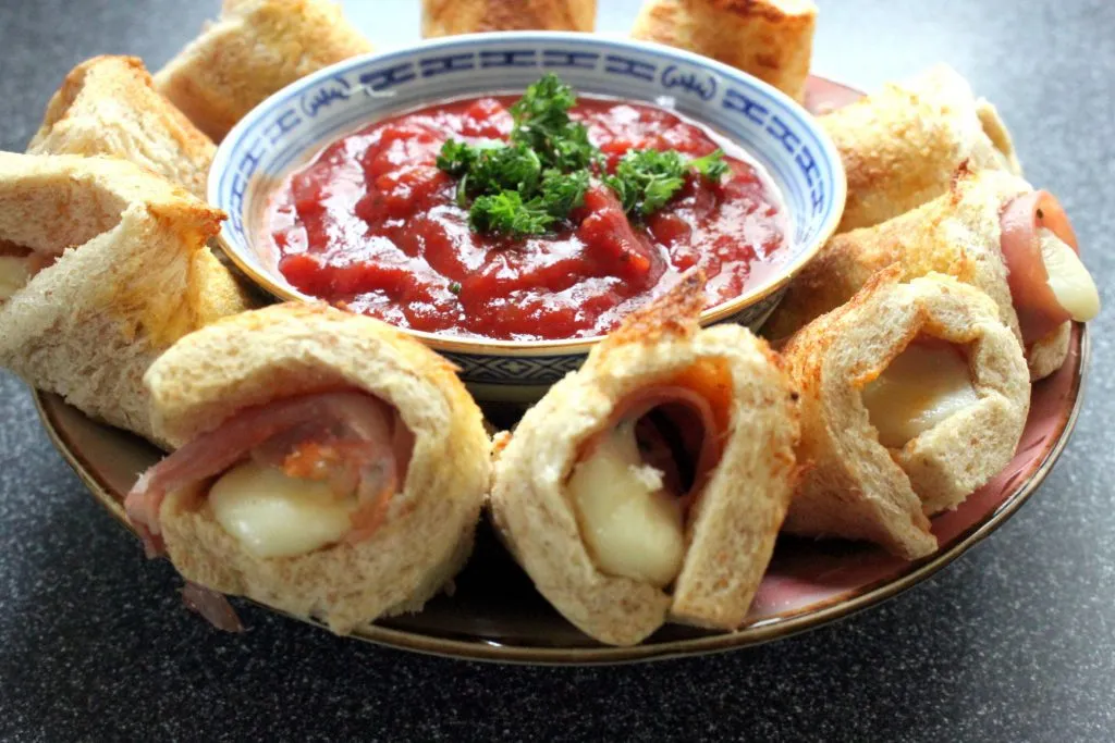 Fertig gebackene, goldbraune Käserollen appetitlich auf einem Servierteller arrangiert