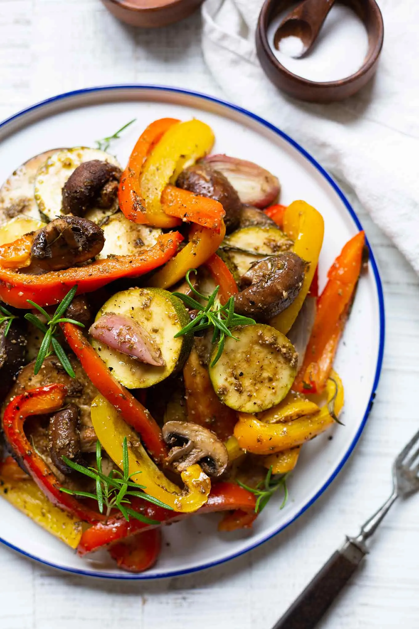 Fertig gebackene italienische Antipasti, angerichtet auf einem Teller mit Oliven und frischen Kräutern