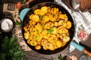 Fertig gebratene Kartoffelscheiben mit Zwiebeln und Speck als Beilage serviert