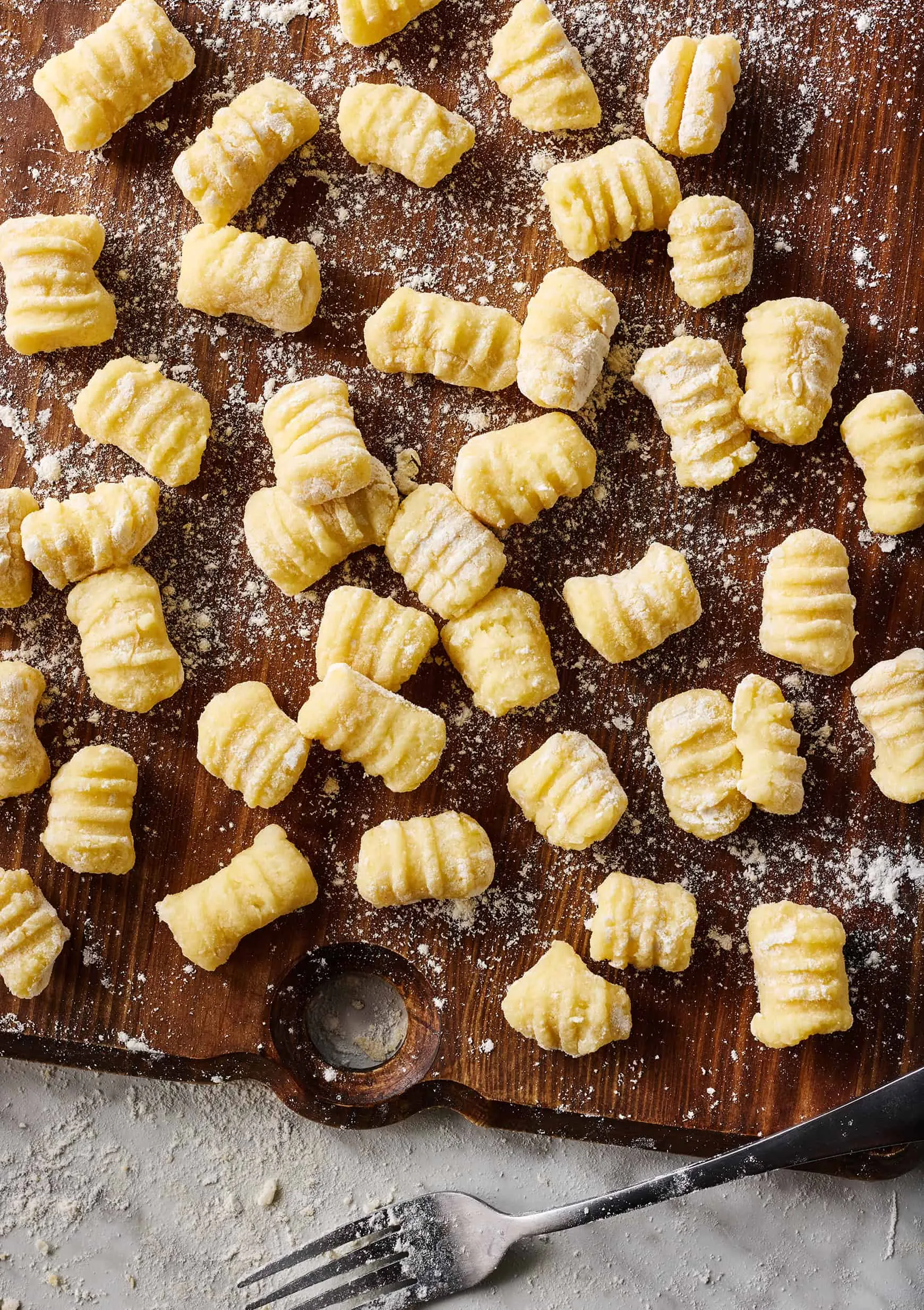 Fertig geformte hausgemachte Kartoffelgnocchi mit Gabelrillen auf einem Backblech.