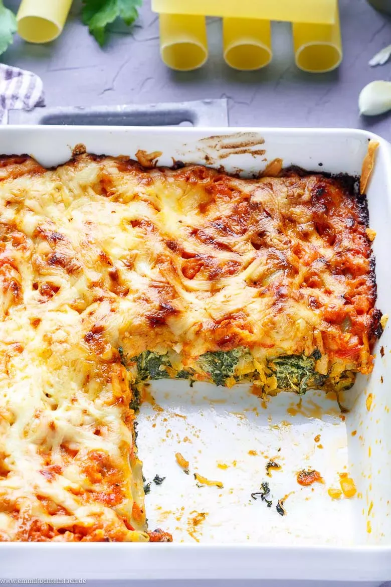 Fertig geschichtete Cannelloni mit Tomaten-Sahne-Soße und Käse, bereit für den Ofen.