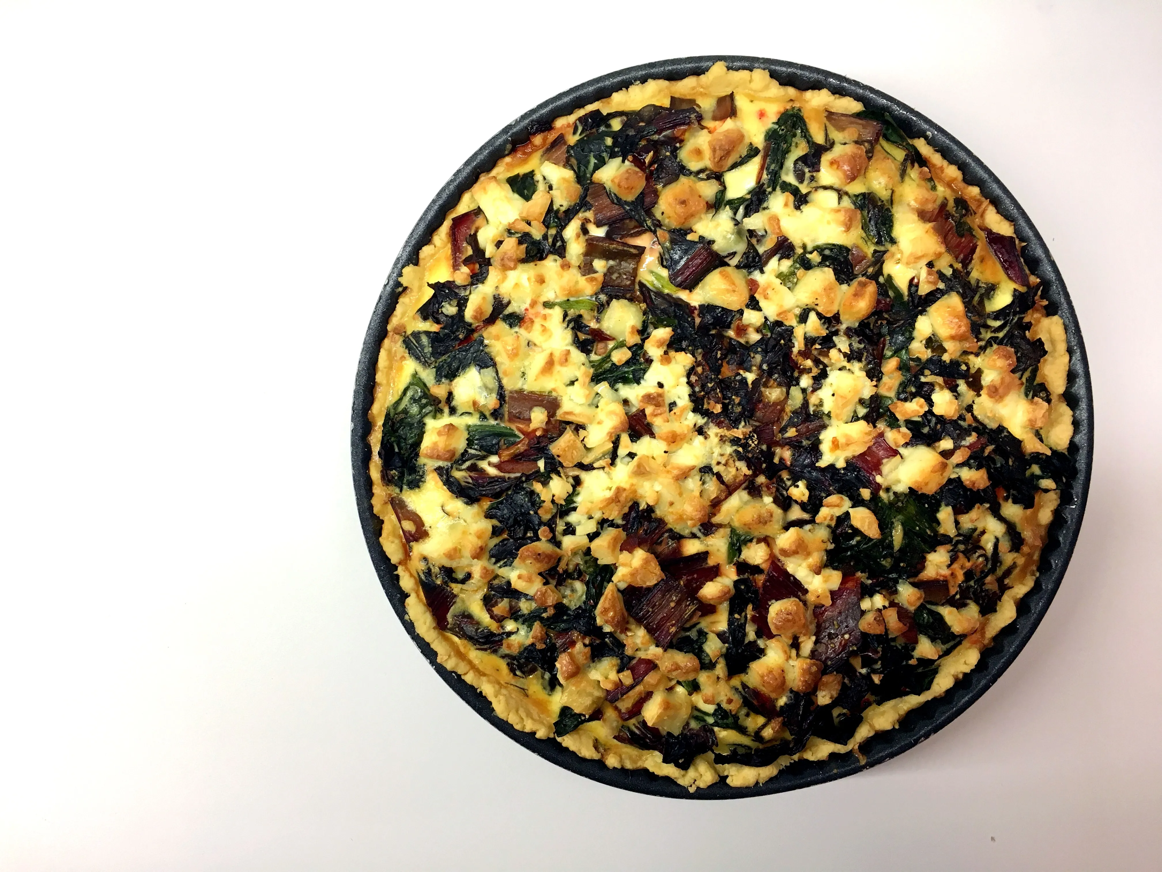Fertige Mangold-Quiche mit goldbraunem Teig und Füllung