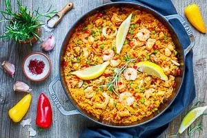 Fertige Paella mit Hähnchen und Meeresfrüchten, garniert mit Zitrone