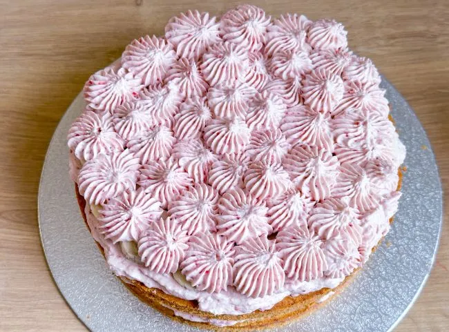 Fertige Schichten der Geburtstagstorte für 1-Jährige mit Creme und kleinen Tupfen verziert