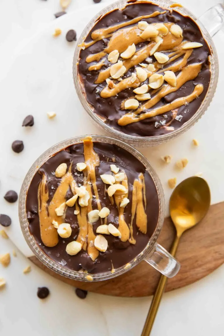 Fertige Snickers Overnight Oats in einem Glas, gekrönt mit knackiger Schokoladenhülle, Erdnussbutter und gehackten Erdnüssen.