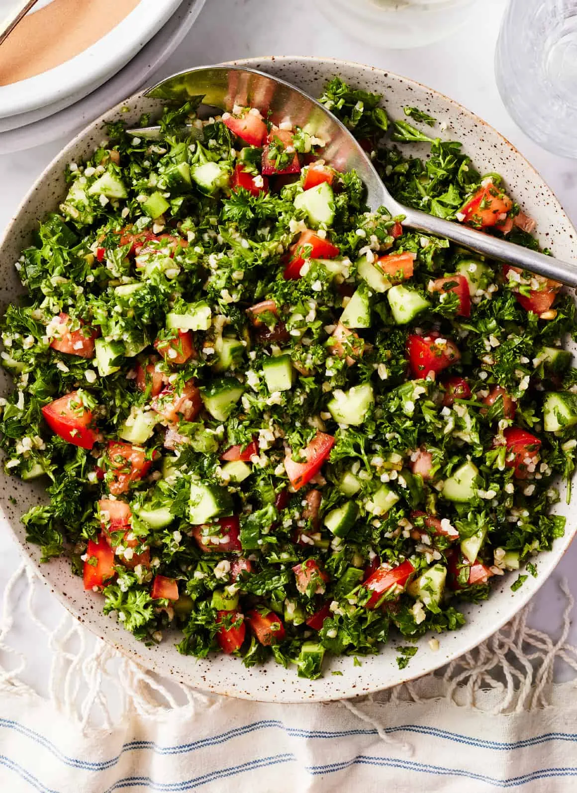 Fertiger Tabouleh Salat in einer gesprenkelten Servierschale mit einem Löffel, appetitlich angerichtet