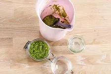 Fertiges Basilikum Pesto wird in ein sterilisiertes Schraubglas gefüllt