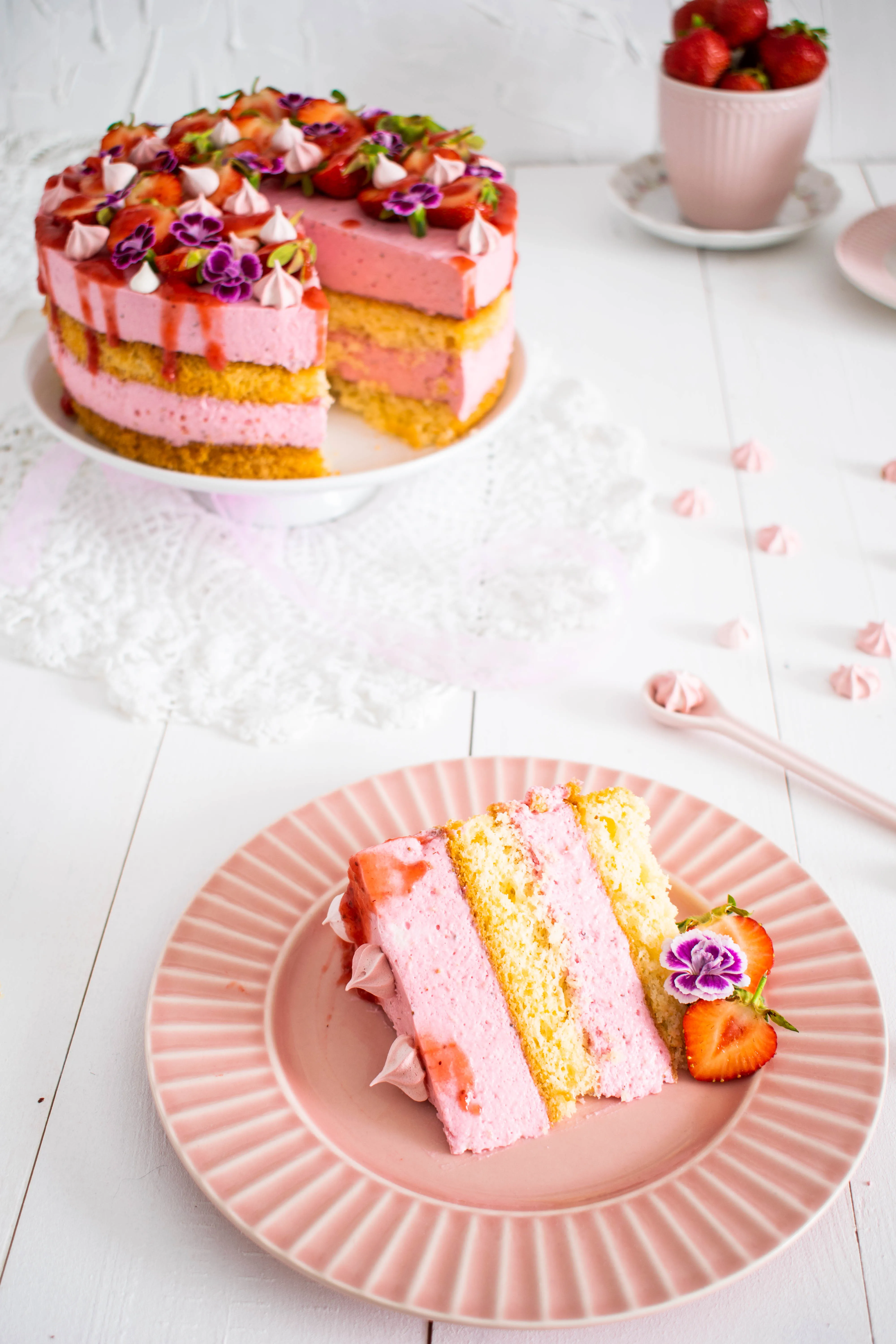 Festlich dekorierte Erdbeersahnetorte mit Blumen und halbierten Erdbeeren als Eyecatcher