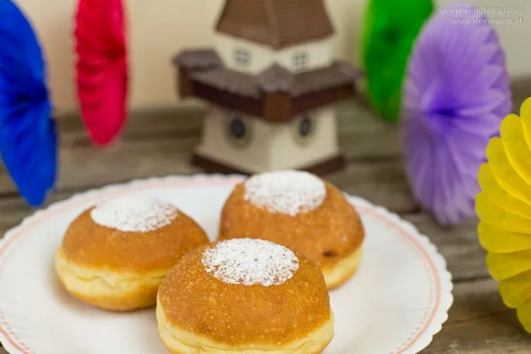 Festlich dekorierte Faschingskrapfen, mit Zucker bestreut und zum Anbeißen köstlich auf einer Platte angerichtet.