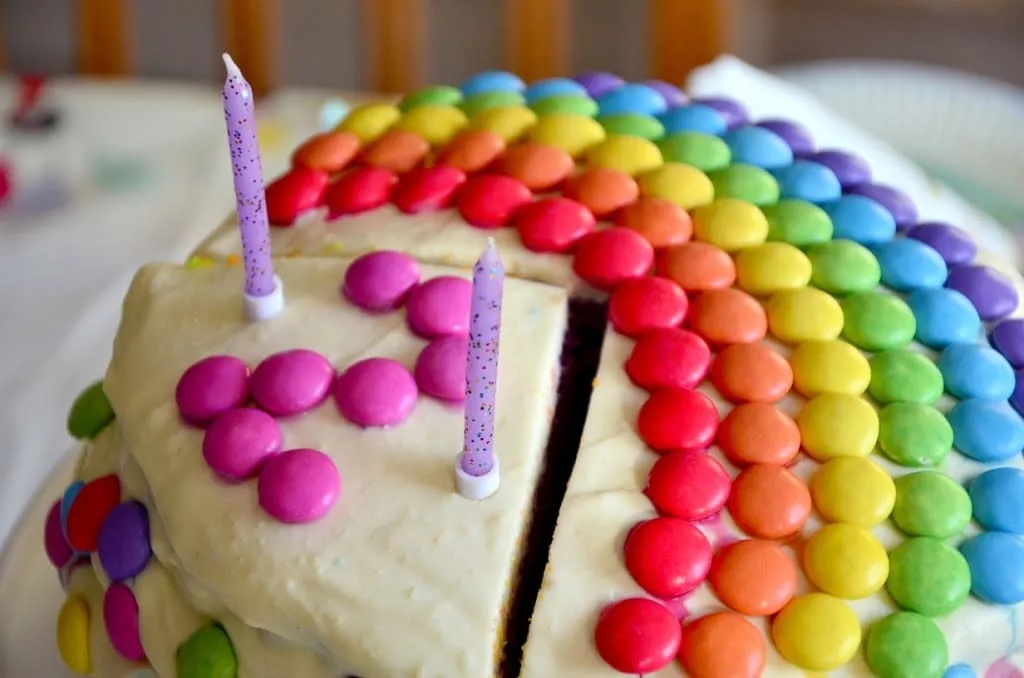 Festlich gedeckter Geburtstagstisch mit der großen Regenbogen Sahne Torte als Mittelpunkt