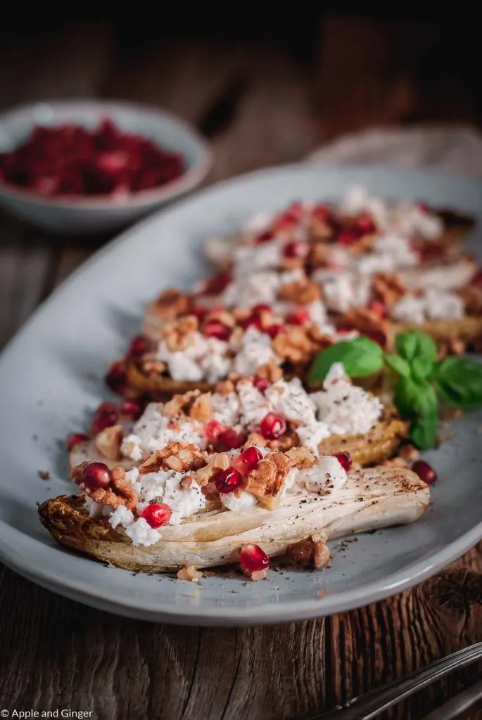 Festliche Chicorée-Schiffchen gefüllt mit Ziegenkäse, Granatapfel und Walnüssen auf einer Servierplatte
