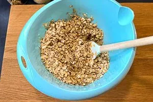 Feuchte Öl-Honig-Mischung wird zu den trockenen Granola Zutaten in einer Schüssel gegeben und gut verrührt.