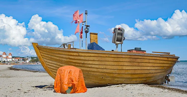Fischerboot am Binzer Strand mit dem Kurhaus im Hintergrund – ein typisches Bild für Ostsee Ferienorte.